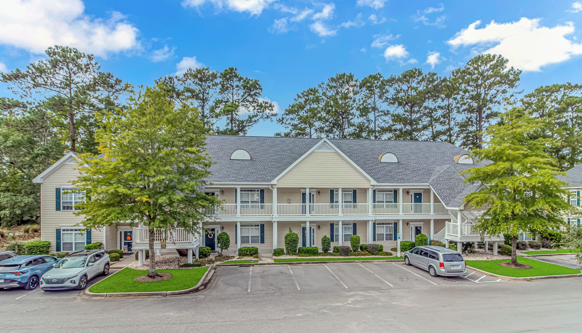 A multi-story residential building with a parking lot in front.