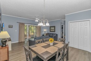 A dining area with a table set for four, a sofa, and a ceiling fan. - The Coastal Catch Ground-Floor Oasis near Beach, Pool & Golf (Little River)