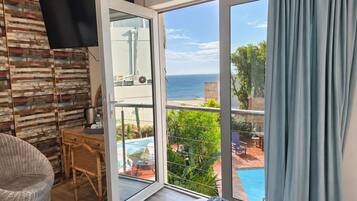Una habitación con un gran ventanal corredero que da a un balcón con piscina y vista al océano.