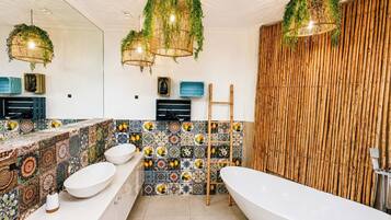Ein Badezimmer mit einer freistehenden Badewanne, einem großen Spiegel und einer Fliesenrückwand mit Obstmotiven.