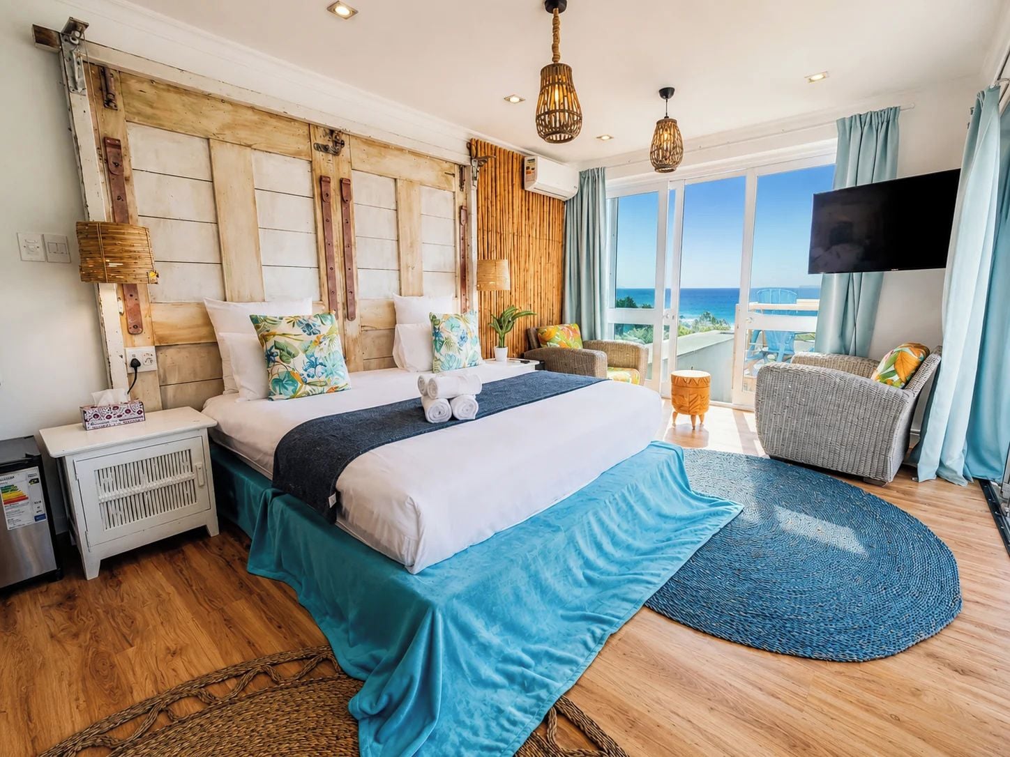Een hotelkamer met een groot bed, een televisie, een balkon met uitzicht en een houten hoofdeinde.