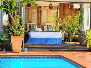 Ein Schlafzimmer mit einem Bett, Kissen und Blick auf den Poolbereich.