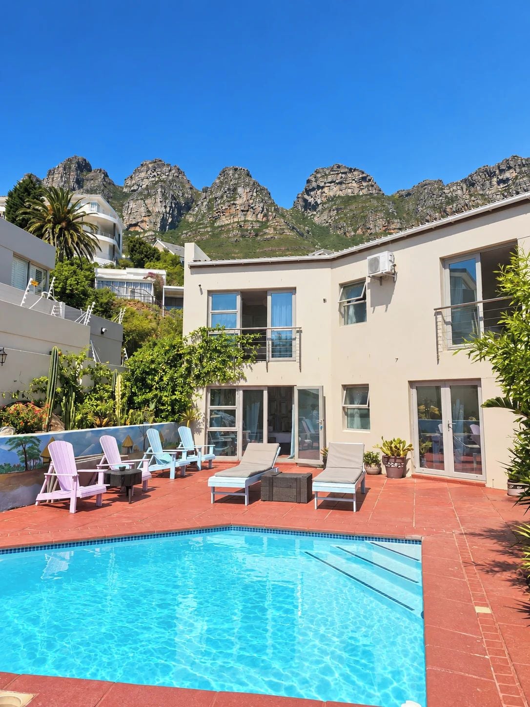 A pool area with lounge chairs and a clear view of mountains in the background.