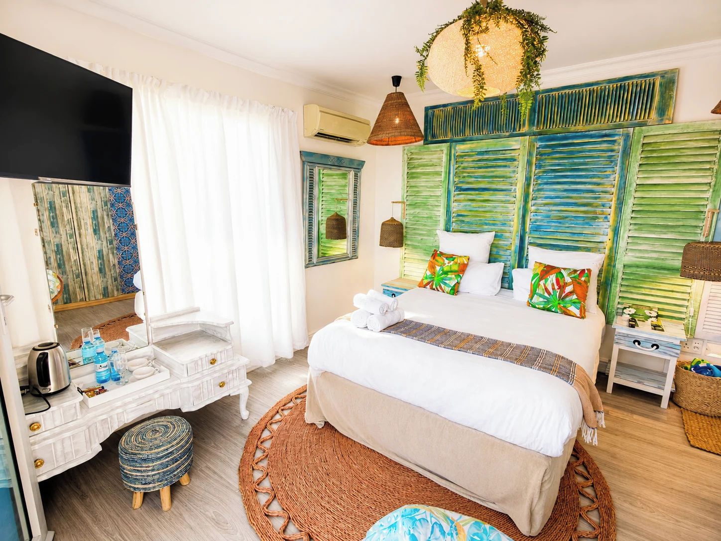 A well-lit bedroom with a bed, bedside tables, a dresser, and a mirror.