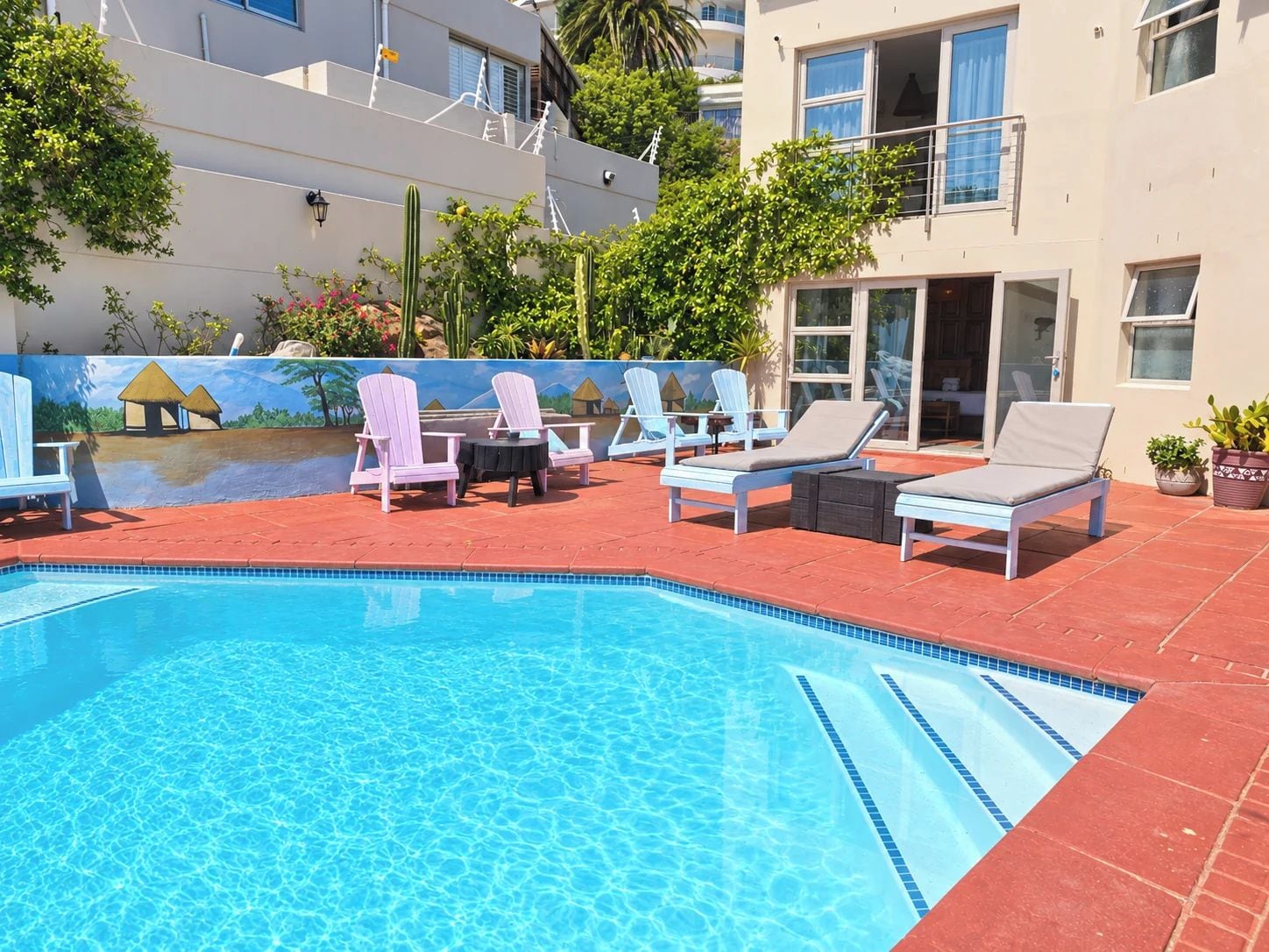 Ein Swimmingpool mit Liegestühlen und einem Wandgemälde.