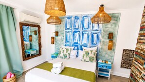 Un dormitorio con cama, mesitas de noche, un espejo y una pared con paneles azules.