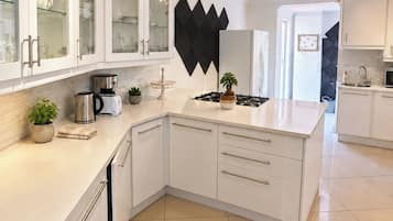 Una cocina moderna con armarios blancos, un adorno de pared negro y una estufa a gas.