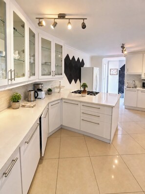 Cozinha moderna com armários brancos, um painel decorativo preto e fogão a gás.