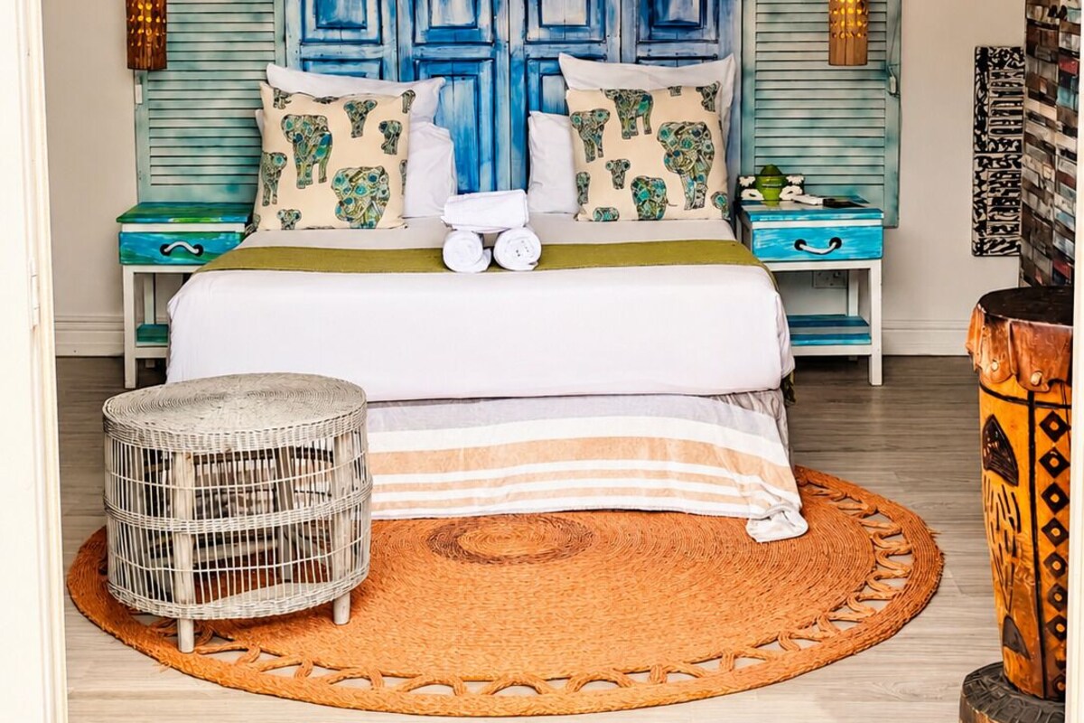Un dormitorio con cama, mesitas de noche, una cesta de mimbre y una alfombra tejida.