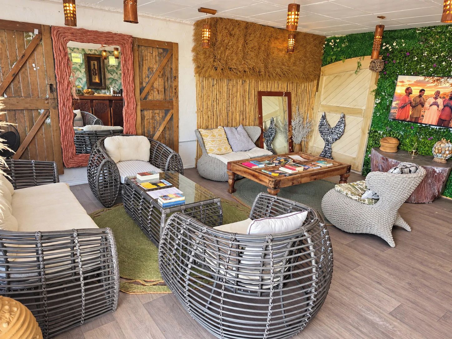 Ein gemütlicher Lounge-Bereich mit Korbmöbeln, einem Holztisch und einer grünen Wand mit Wandgemälde.