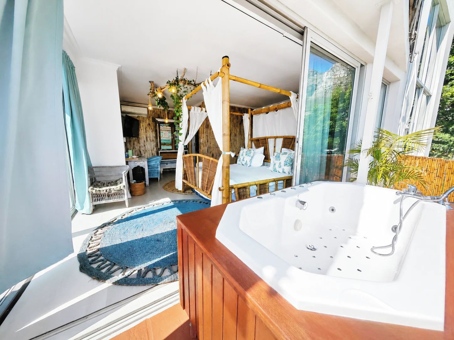 A modern room with a large window, a wooden floor, a white bathtub, and a bed with a canopy.