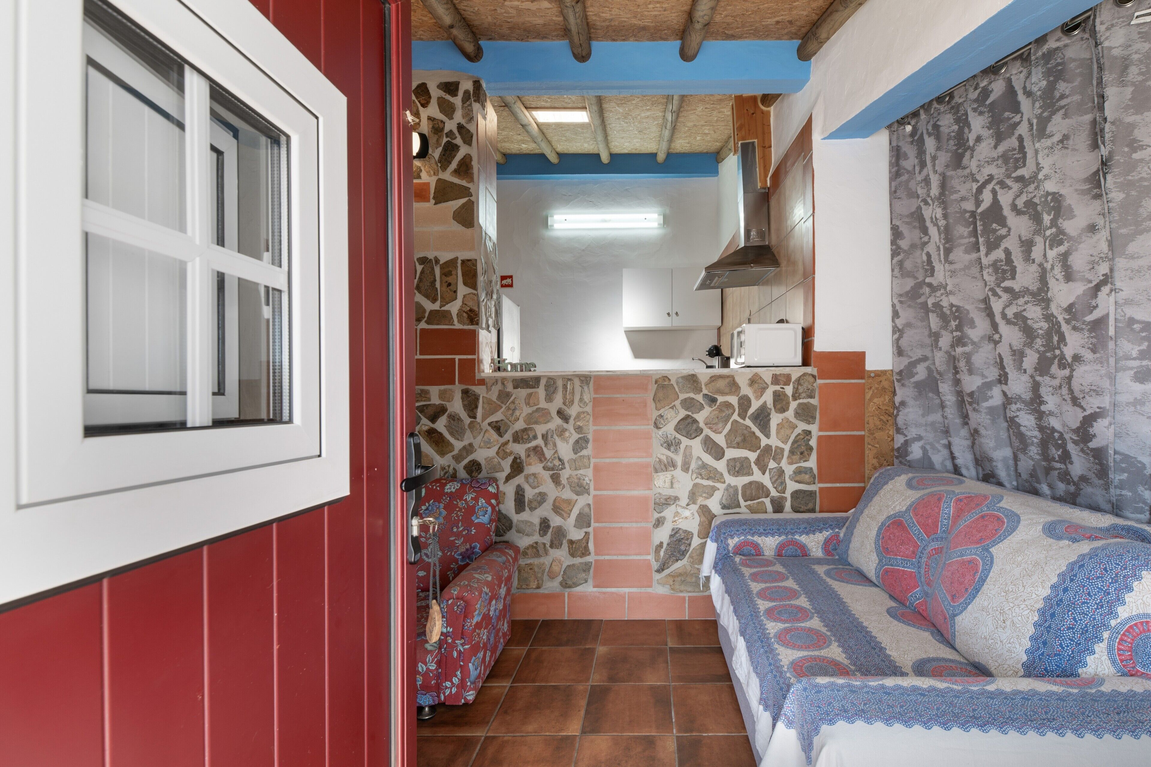 Un espacio habitable compacto con kitchenette, un sofá y una cama con diseño estampado.