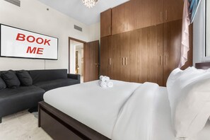 Ein Schlafzimmer mit einem Bett, einem Schlafsofa, Holzschränken und einem Schild mit der Aufschrift 'BOOK ME'.