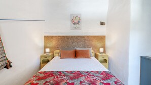 Una camera da letto con un letto, due comodini con lampade, un'opera d'arte appesa al muro e una coperta con motivo.