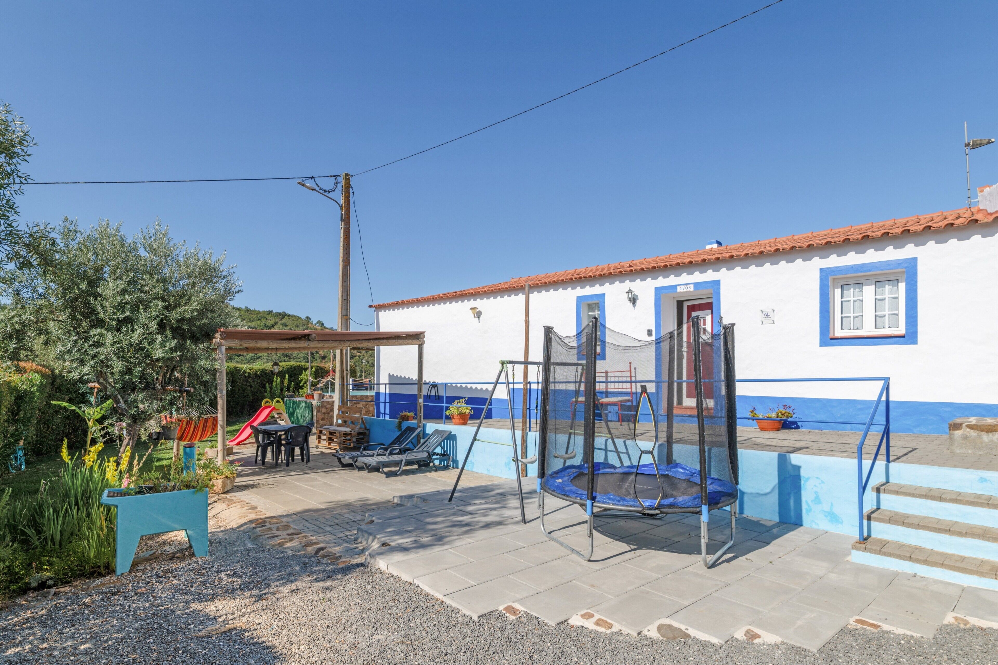 A house with a patio, a trampoline, and a slide.