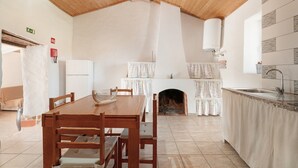 Ein Essbereich mit Holztisch und Stühlen, einem Kamin und einer Küche inklusive Spüle und Herd.