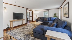 A living room with a sofa, a TV on a stand, a small table, and a patterned rug. - 1.5 Miles to Kennebunk BEACH|Sleeps 12| Pet friendly (Kennebunk)