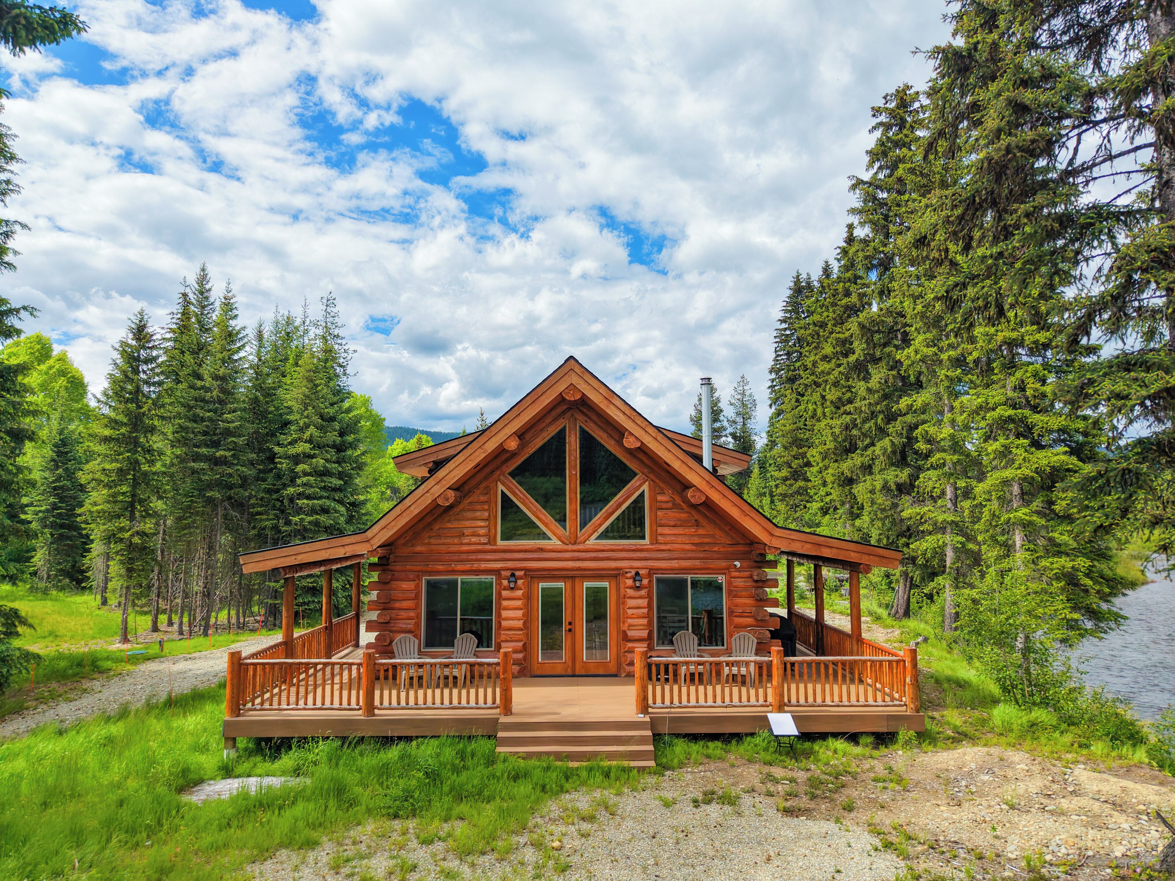 A log cabin with a deck, large windows, and a chimney.