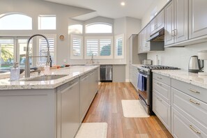 A modern kitchen with a large island, stainless steel appliances, and a view of the outdoors. - Upscale Chandler Executive Home | Resort Backyard (Chandler)