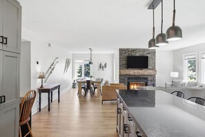 Eine moderne Küche mit Kamin aus Stein, Essbereich und einer großen Kochinsel.