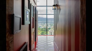Un pasillo con piso a cuadros, vista a través de un vidrio y una lámpara fijada a la pared.