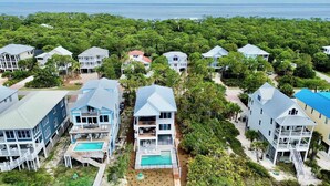 A residential area with multiple houses, a swimming pool, and a view of the ocean. - NEW- 6 bedroom-Private Pool- Pet Friendly (Saint George Island)