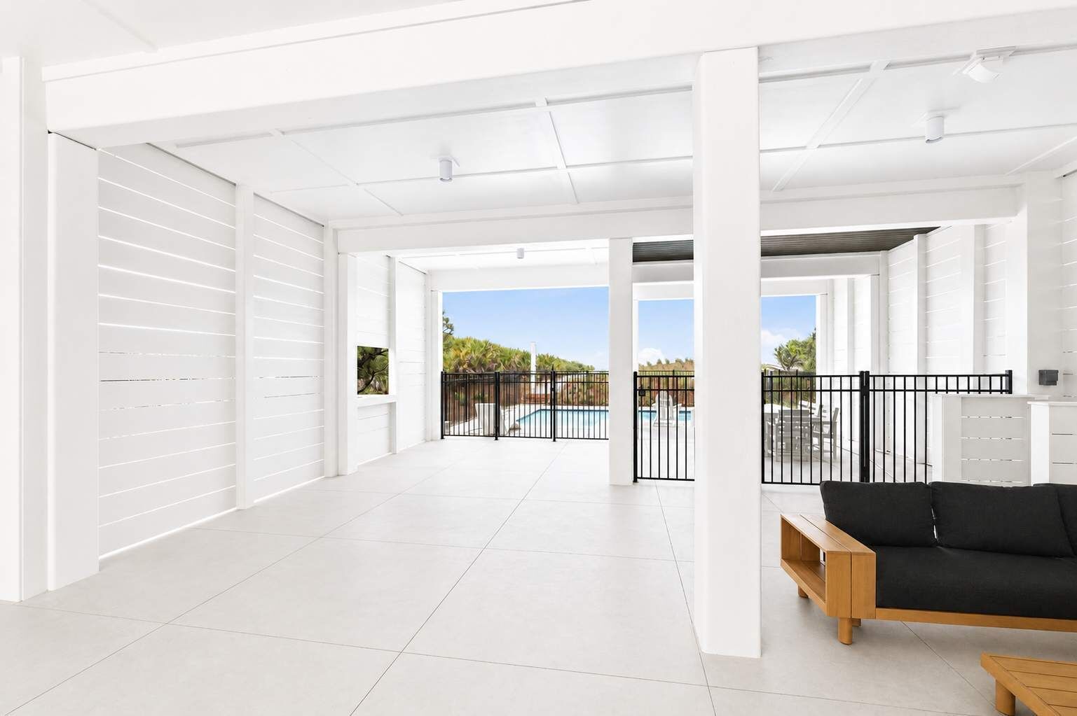 A spacious indoor area with a pool view, white walls, and a black sofa.