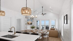 A modern kitchen with a central island, a dining area with a view, and a ceiling fan. - NEW- 6 bedroom-Private Pool- Pet Friendly (Saint George Island)