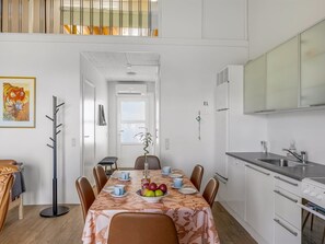 Eine moderne Küche mit weißen Schränken, einem Esstisch gedeckt mit Tellern, Tassen und einer Obstschale.