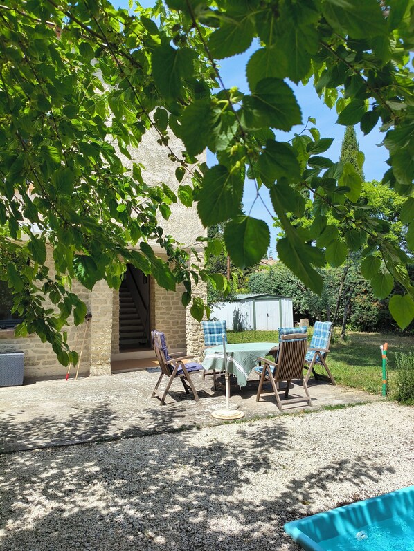 Eine Terrasse mit Tisch und Stühlen, ein kleiner Pool und ein Steinhaus im Hintergrund.