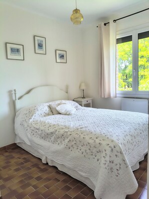 Ein Schlafzimmer mit einem Bett, einem Nachttisch, einer Lampe und gerahmten Bildern an der Wand.