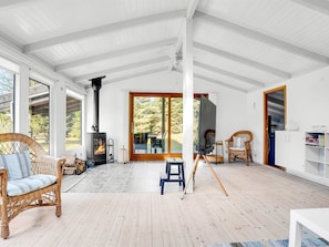 Ein geräumiges Zimmer mit großem Fenster, Kamin, Korbmöbeln und Fernseher.