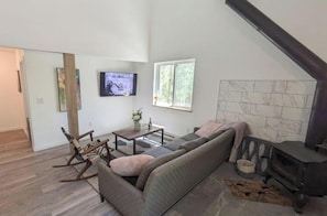 Ein Wohnzimmer mit einer Couch, einem Fernseher, einem Kamin und einem Fenster.