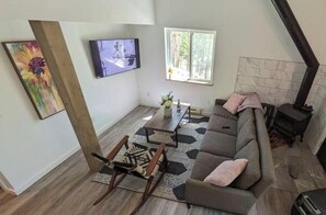 Ein Wohnzimmer mit einer Couch, Couchtisch, Fernseher und Kamin.