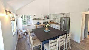 Een moderne keuken met een centraal eiland, witte kasten en roestvrijstalen apparatuur.