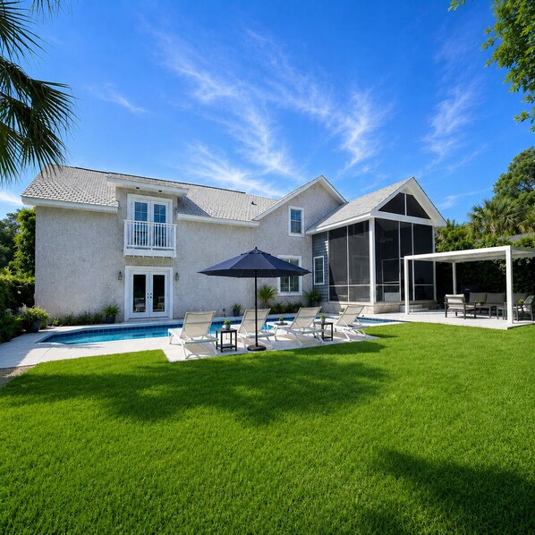 Une maison à deux étages avec une piscine, un espace salon extérieur et une terrasse couverte.