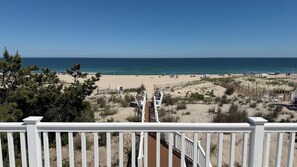 Blick auf einen Strand vom Balkon mit Holzterrasse, Sandstrand und Meer.