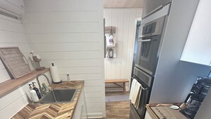 Et køkken med en bordplade i fiskebensmønstret træ, rustfrie hvidevarer og en træbænk.