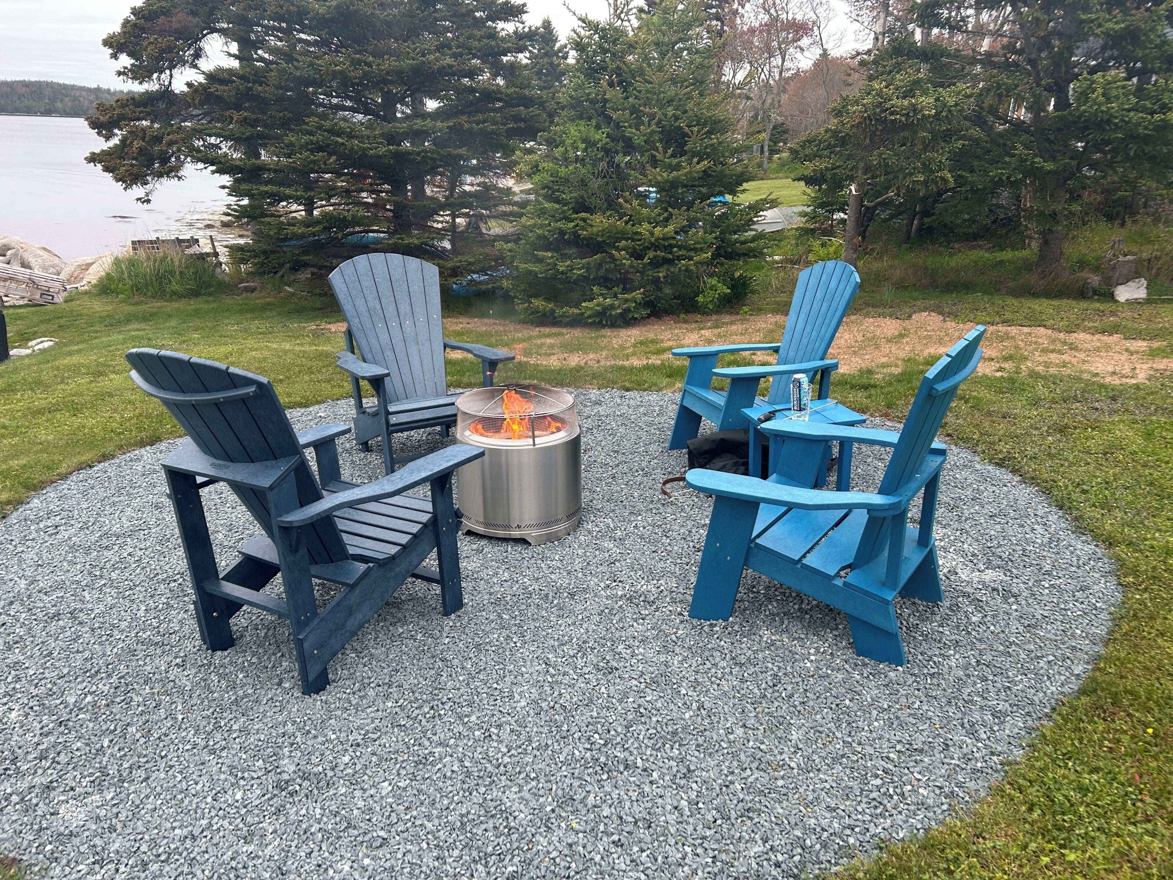 A circular seating arrangement with four Adirondack chairs around a central fire pit.