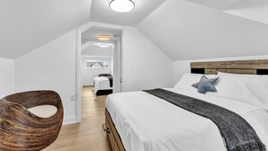 Une chambre à coucher avec un lit, une chaise en osier, une tête de lit en bois et un luminaire au plafond.