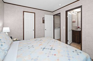 A bedroom with a bed, a nightstand, a lamp, a dresser, and a mirror.