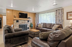 Ein Wohnzimmer mit Kamin aus Stein, Ledersofas und einem flachbildfernseher, der darüber angebracht ist.