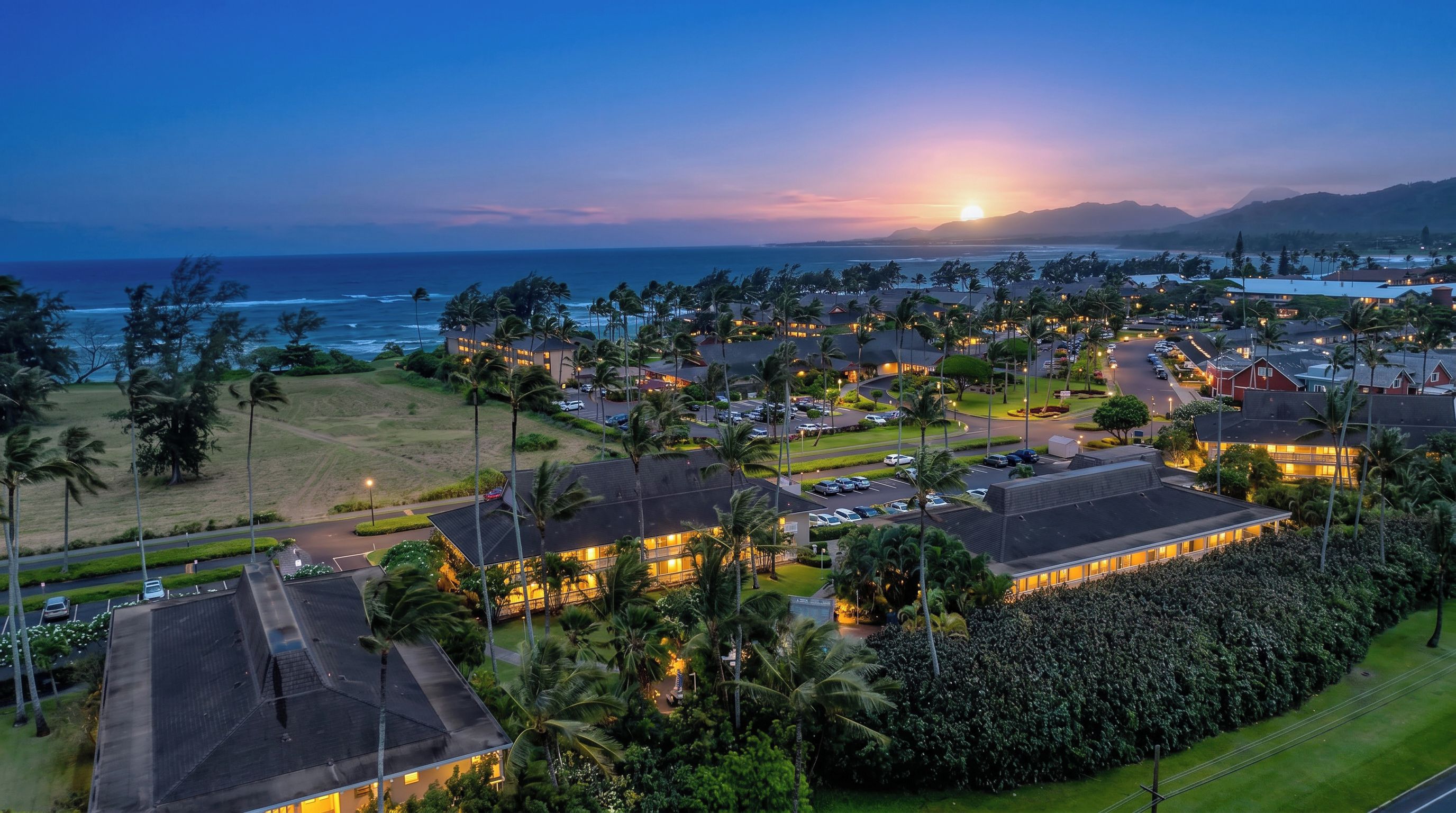 A coastal resort area with multiple buildings, roads, and palm trees.