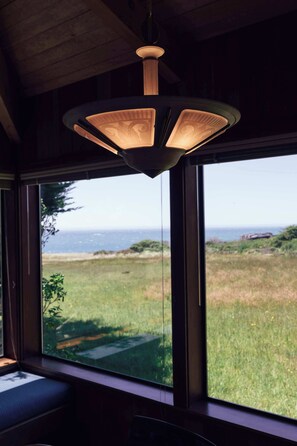 Ein Zimmer mit großem Fenster und Blick auf das Meer und eine grüne Landschaft.