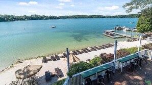 Une vue sur le lac, avec un quai, des chaises longues et une terrasse.