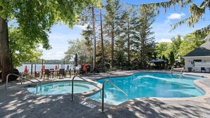Une piscine dotée d’une terrasse en mosaïque hexagonale, entourée d’arbres et agrémentée d’un espace salon abrité.