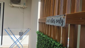 A room with a wooden fence, a sign reading 'Good vibes only,' a blue laundry stand, and a small green plant. - Relax and enjoy the amazing view! Great for family, couple od single travelers! (Bar)
