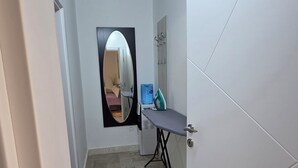 A narrow hallway with a tiled floor, a door with a mirror, and a small ironing station with an iron and water dispenser. - Relax and enjoy the amazing view! Great for family, couple od single travelers! (Bar)