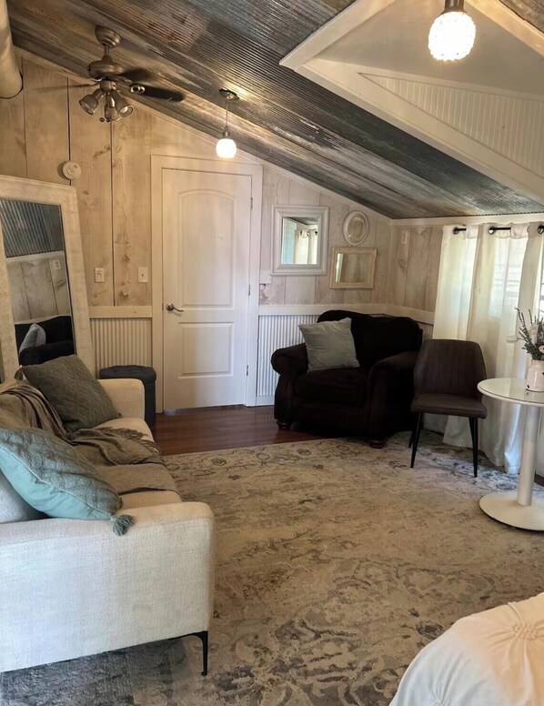 A cozy room with a ceiling fan, a round table, a sofa, and a chair.