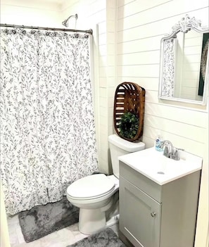 Une salle de bain Ă©quipĂ©e de toilettes, dâun lavabo, dâun miroir et dâun rideau de douche.